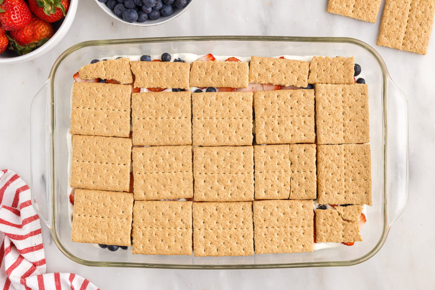 Graham crackers layered over the berries in a baking dish