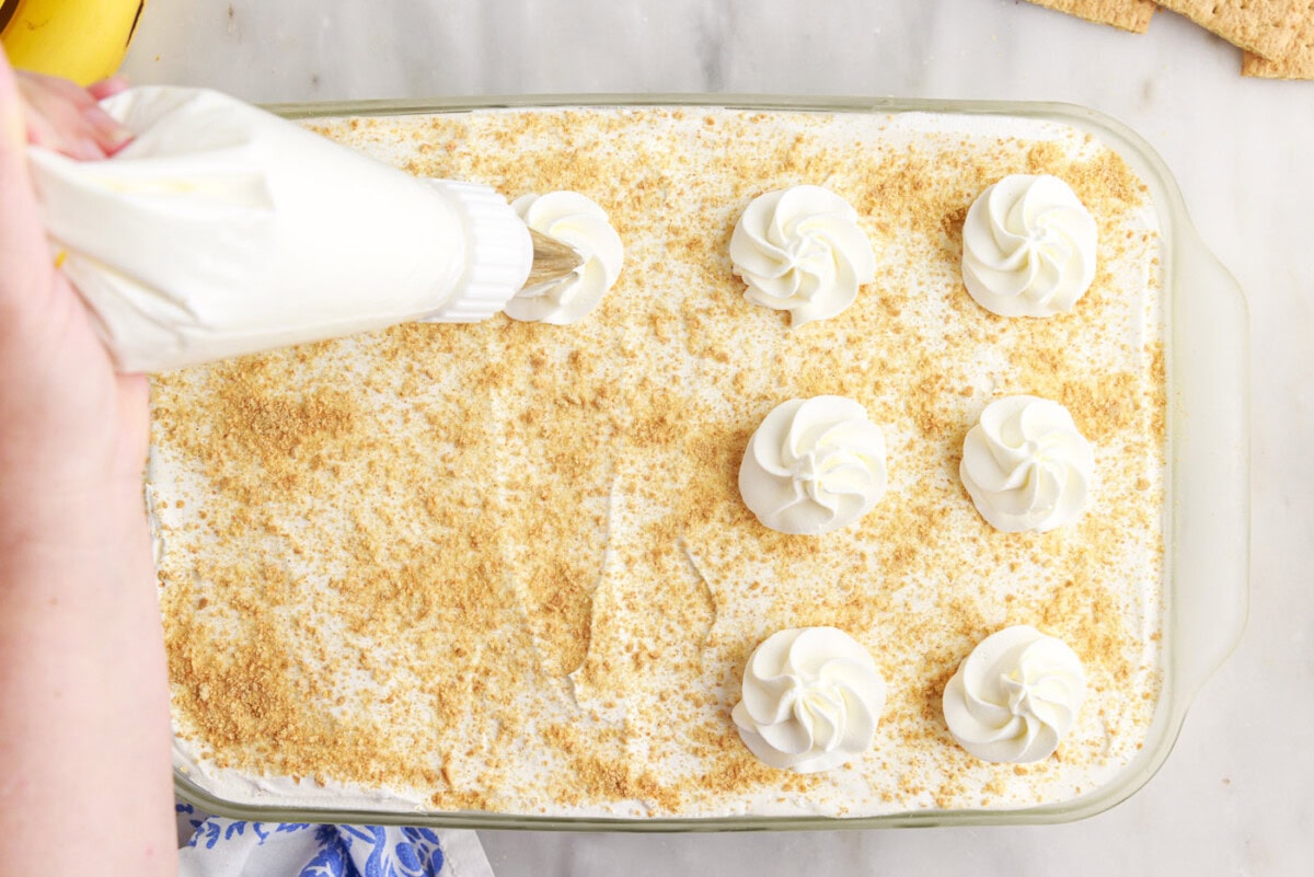 piping whipped cream on top of banana cream pie icebox cake
