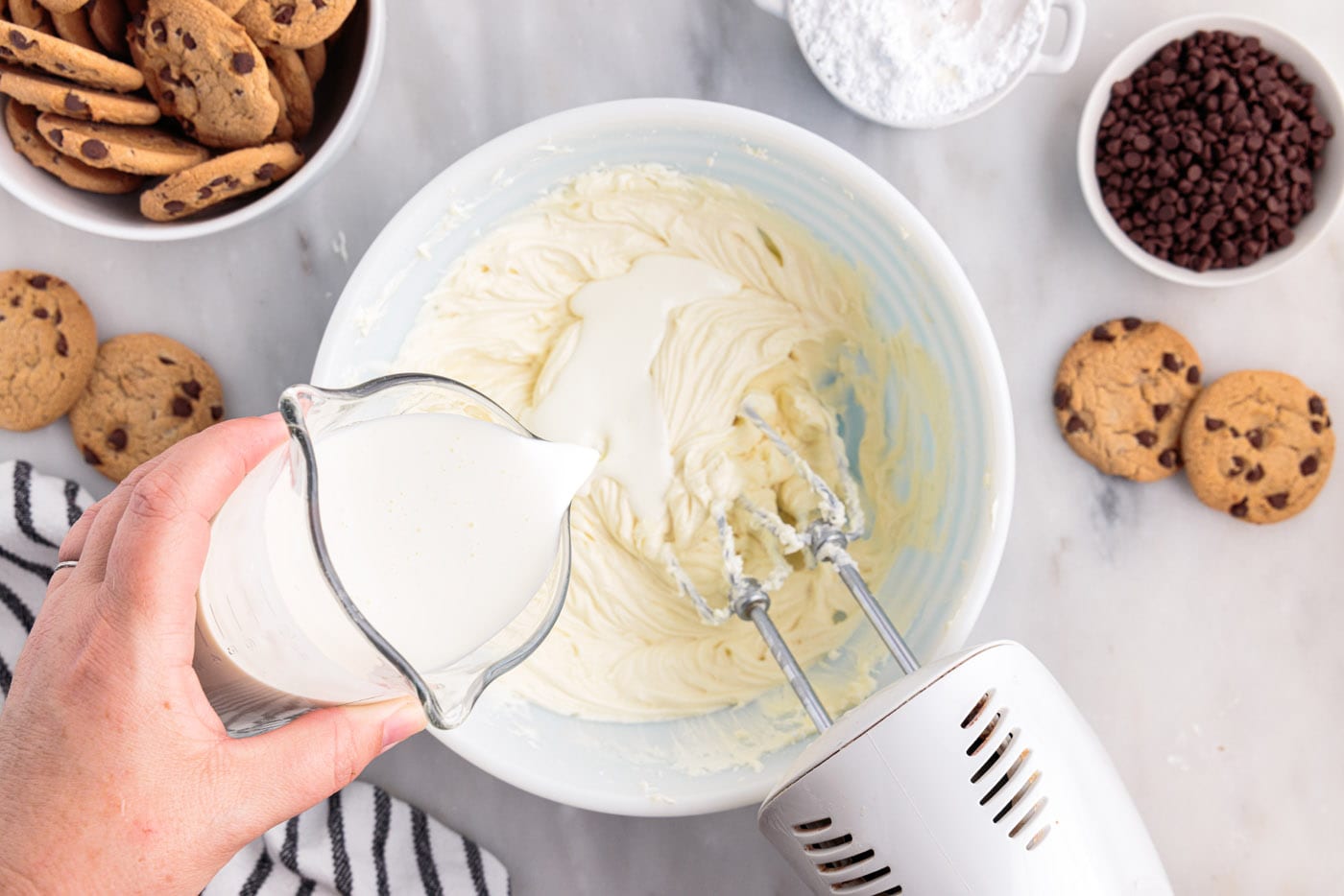 pouring heavy cream into cream cheese mixture in a bowl