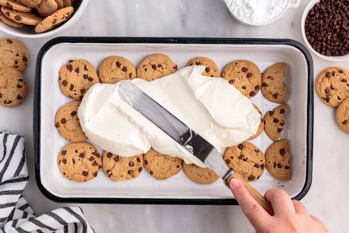 spreading whipped cream cheese on top of chocolate chip cookies