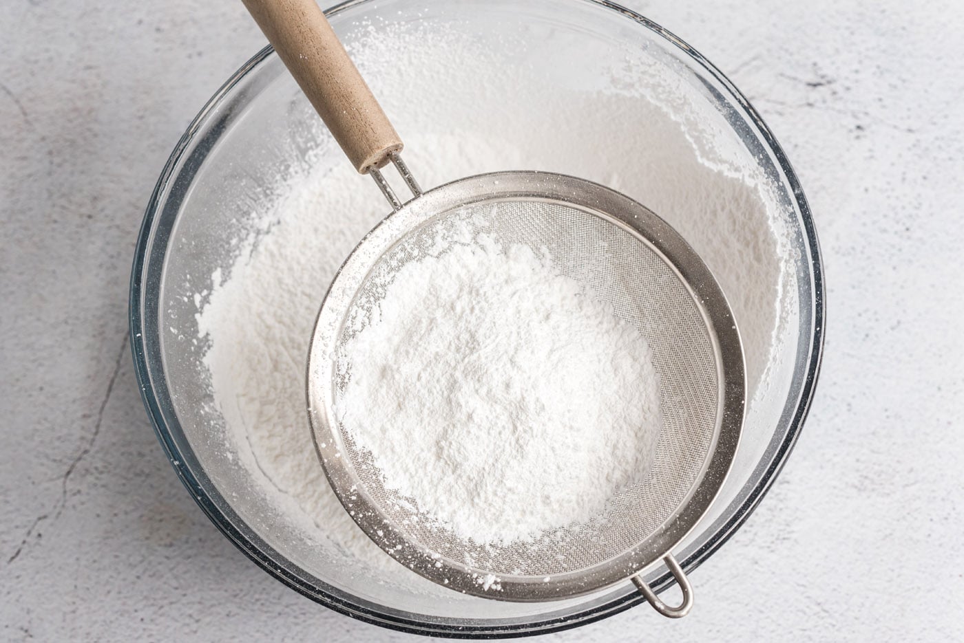 sifting powdered sugar in a bowl