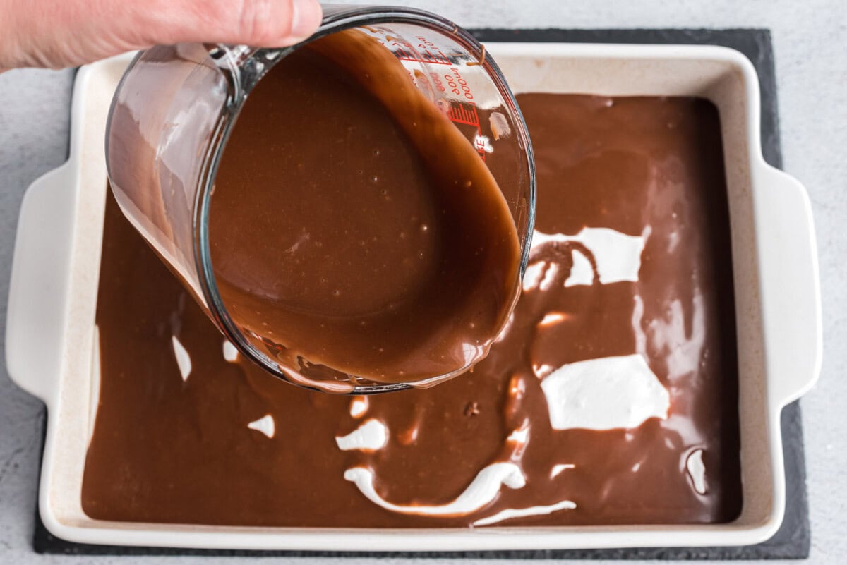 pouring melted chocolate frosting over coke cake