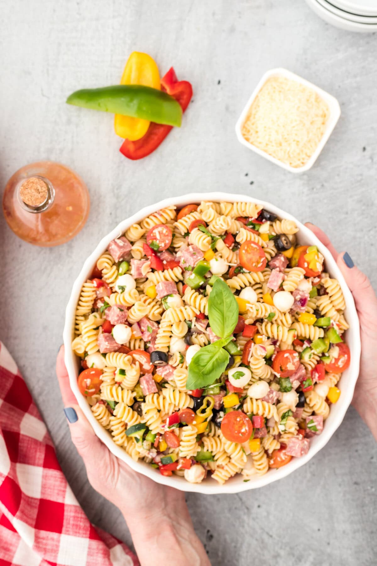 hands picking up a bowl Italian Pasta Salad