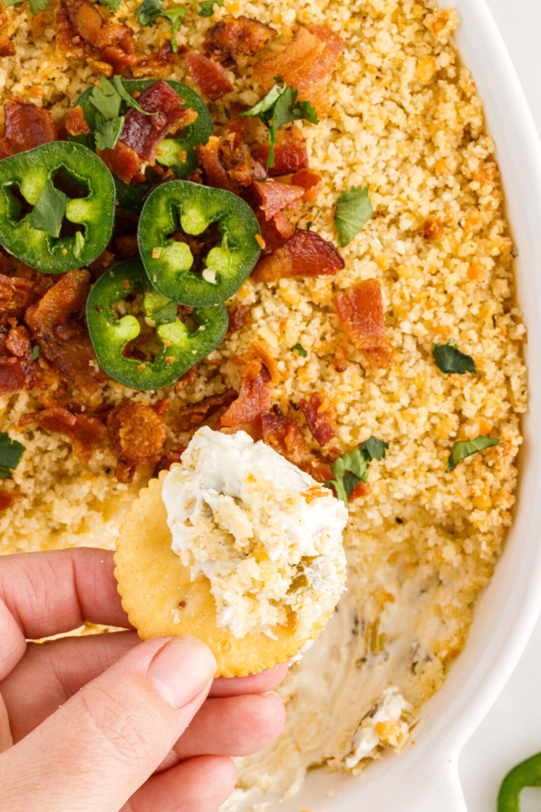 hand lifting chip from Jalapeno Popper Dip