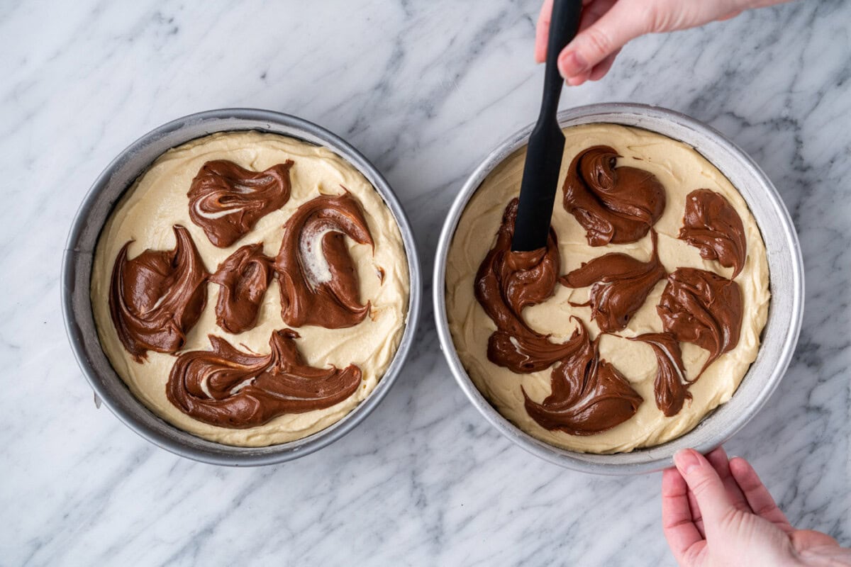 swirling chocolate batter into yellow batter in pans