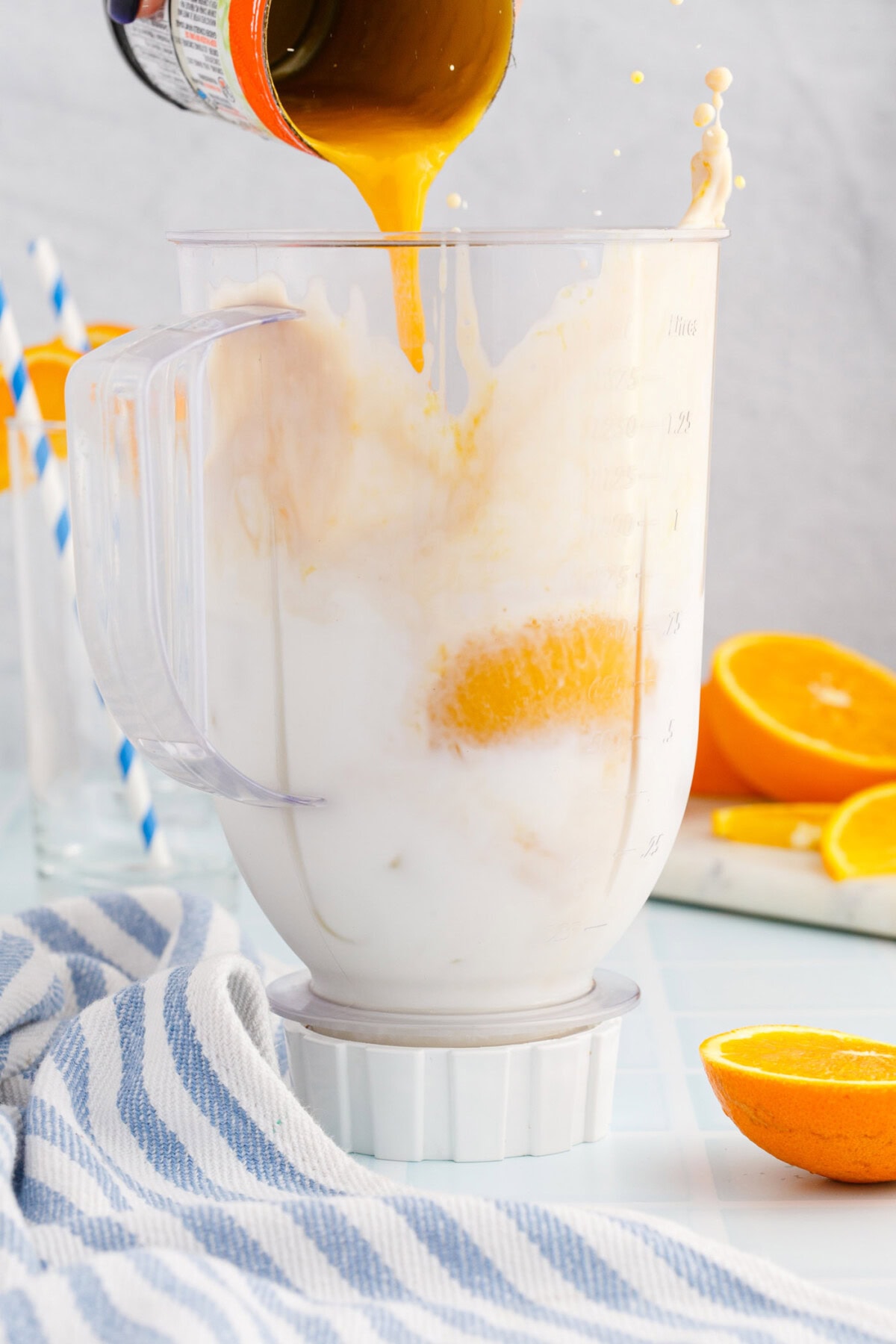 pouring orange julius ingredients into a blender