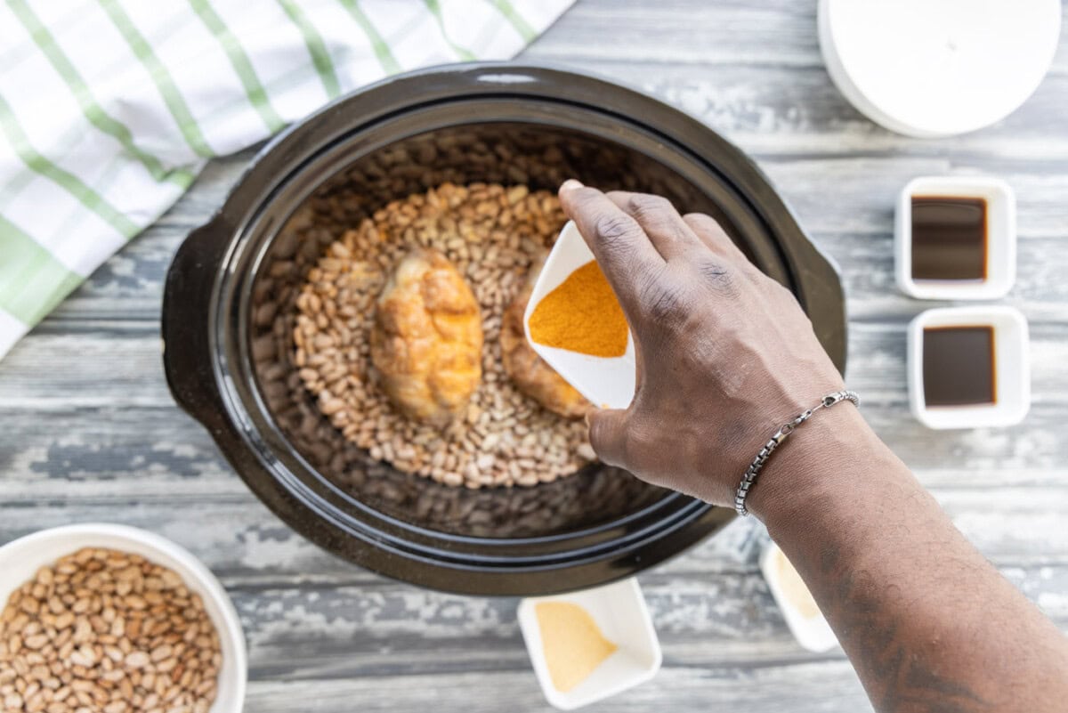 sprinkling seasonings over turkey tails and pinto beans