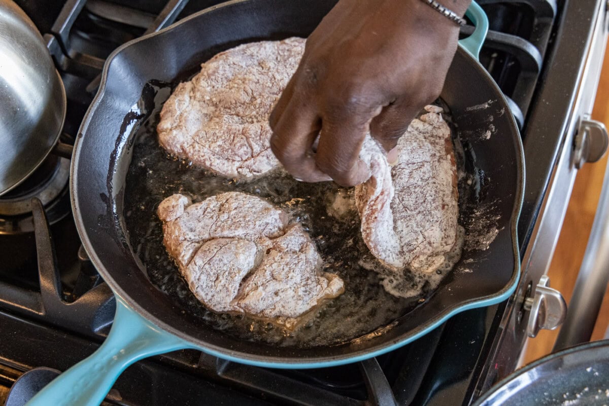 adding veal cutlets to a skillet