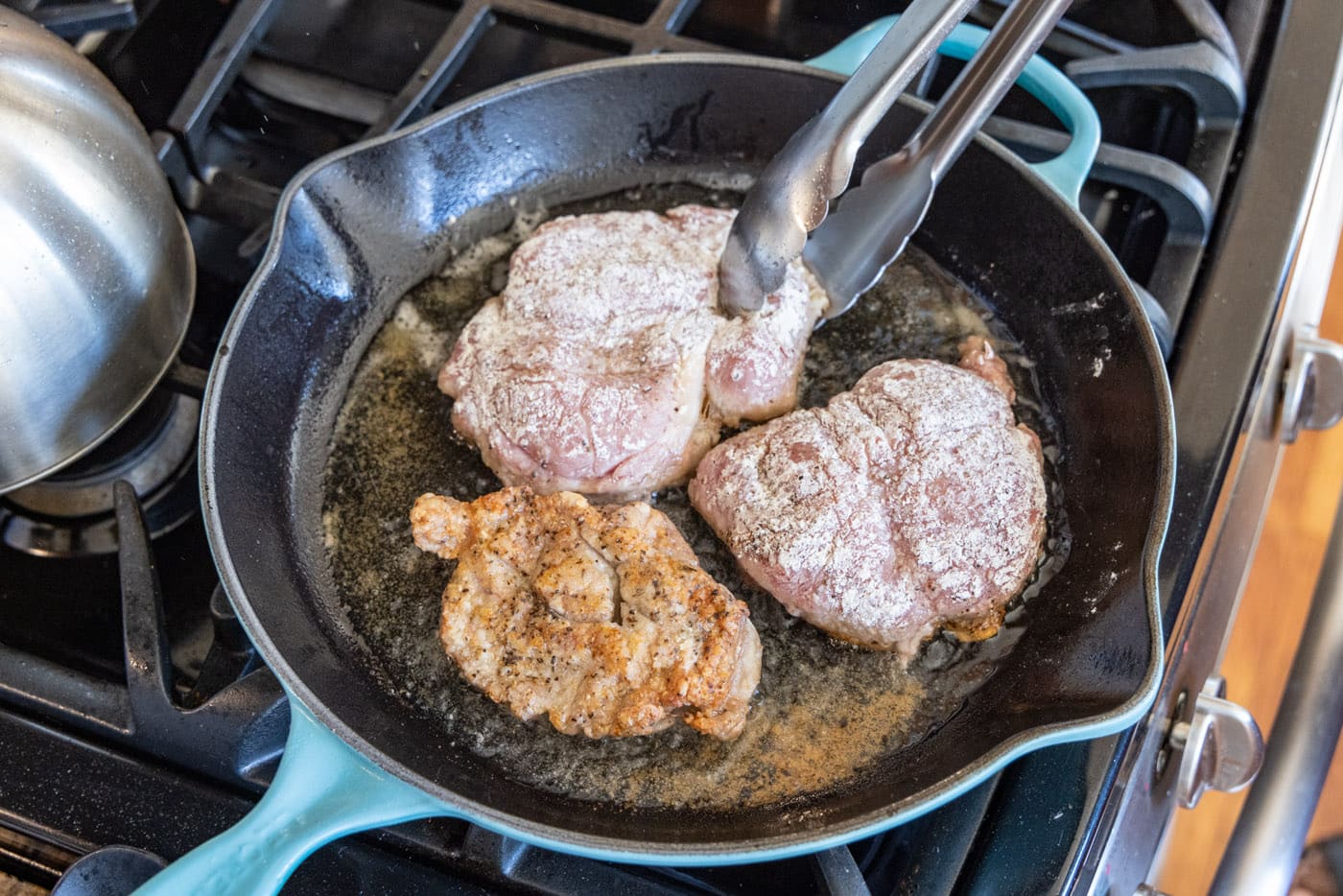 flipping flour dredged veal in a skillet