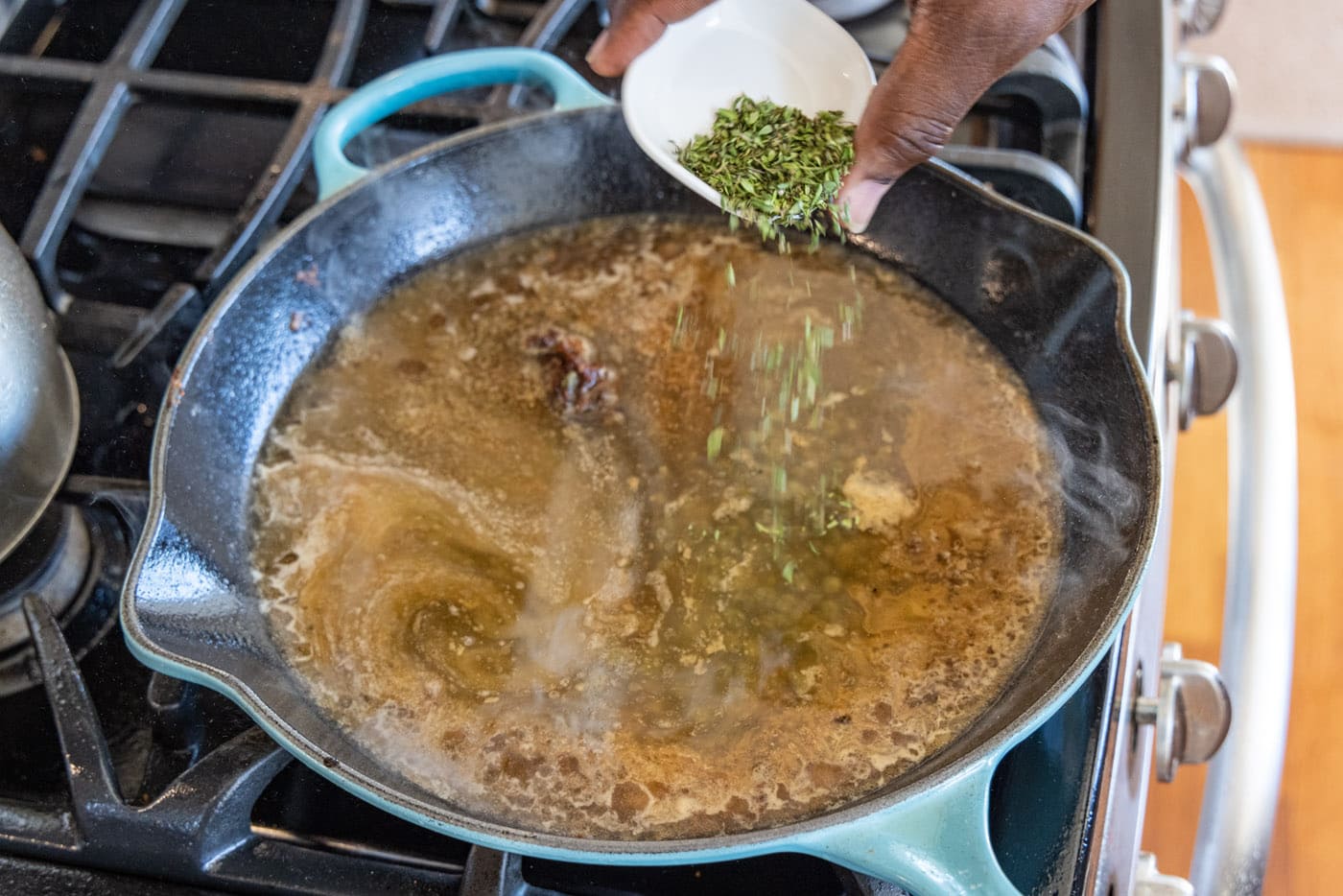 sprinkling thyme into veal piccata sauce