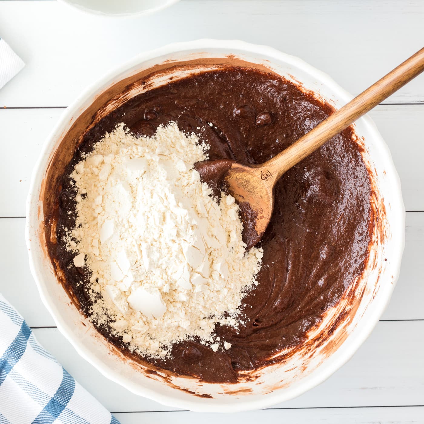 wooden spoon stirring flour into brownie batter