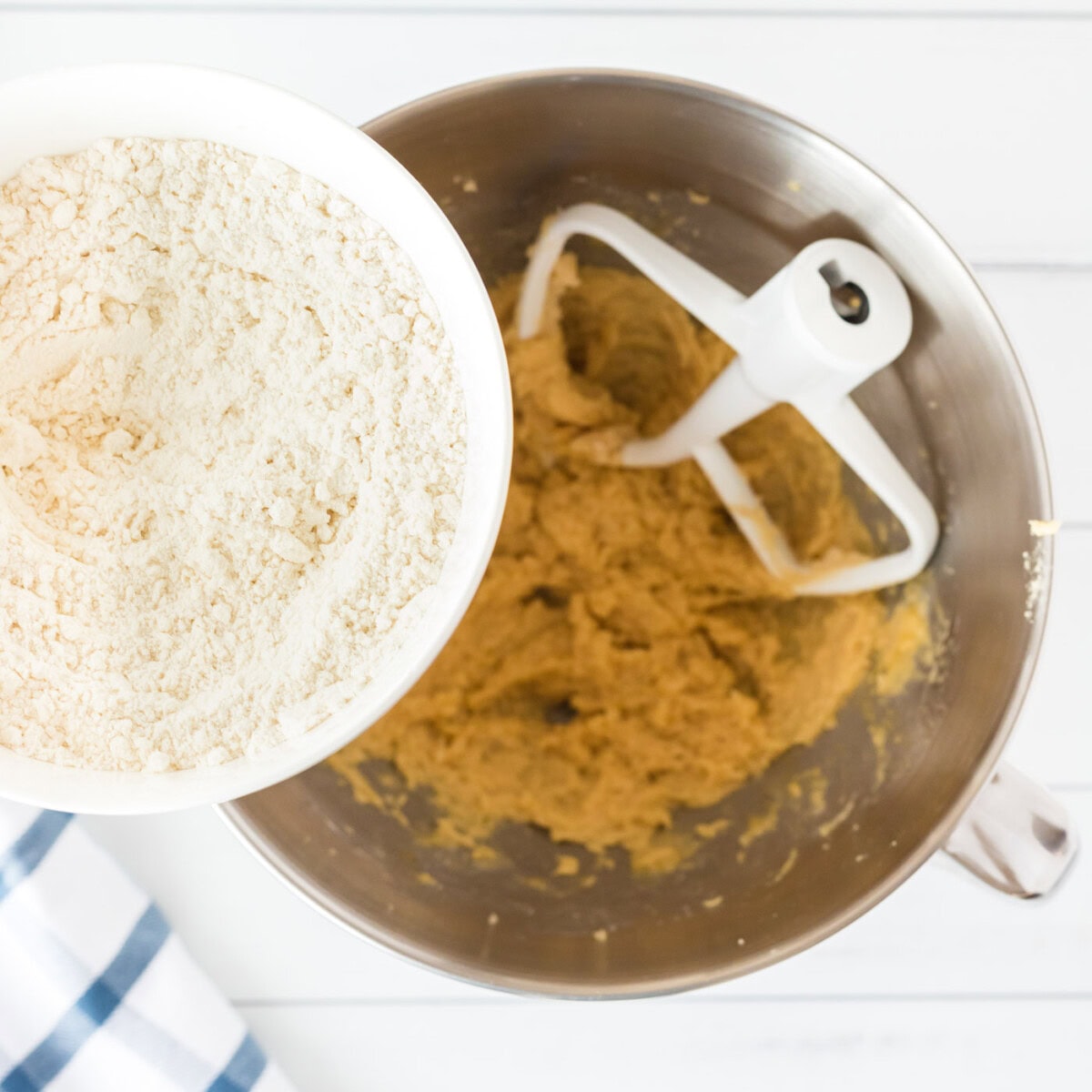 adding flour into cookie dough in a bowl