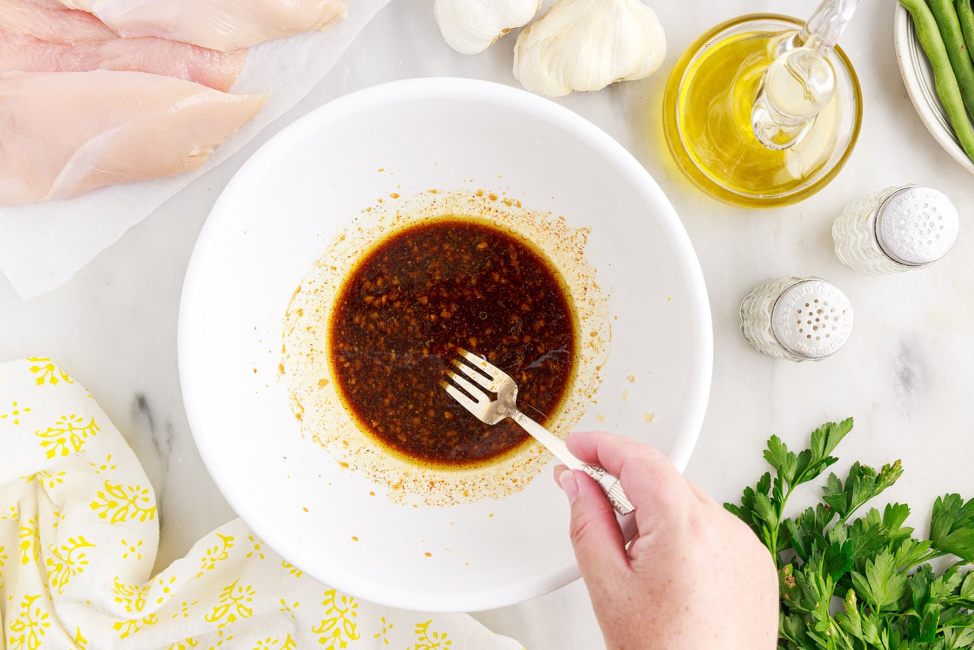 fork whisking chicken marinade in a bowl