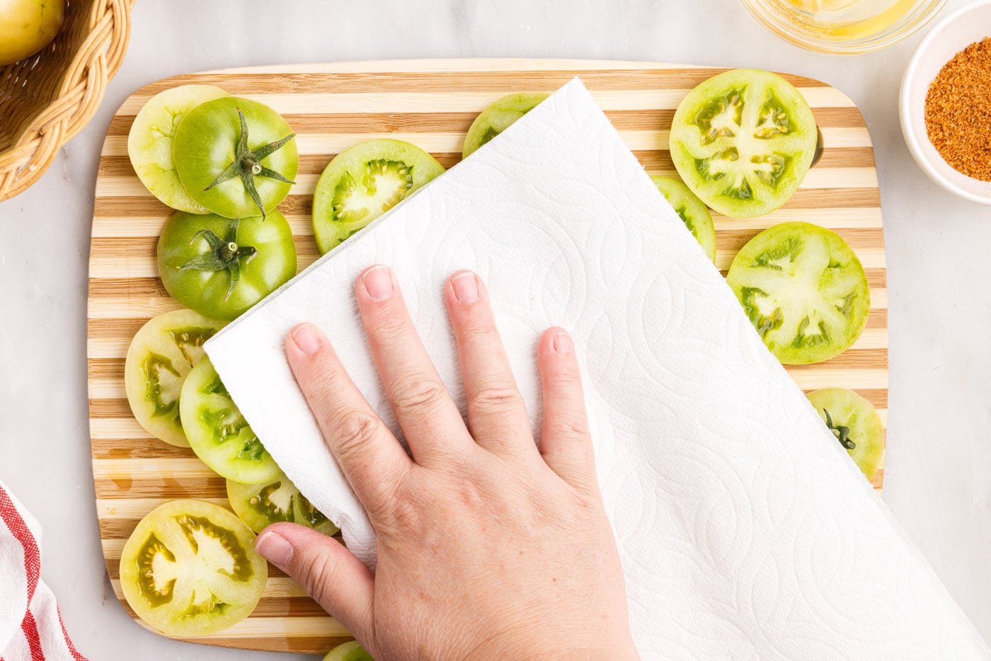 patting sliced green tomatoes dry with a paper towel