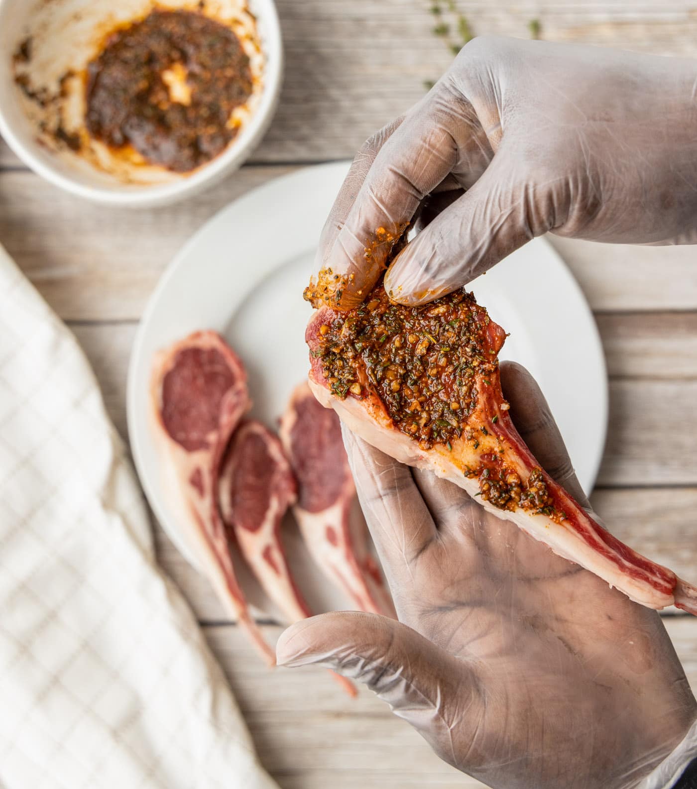 hands rubbing spices onto lamb loin chops
