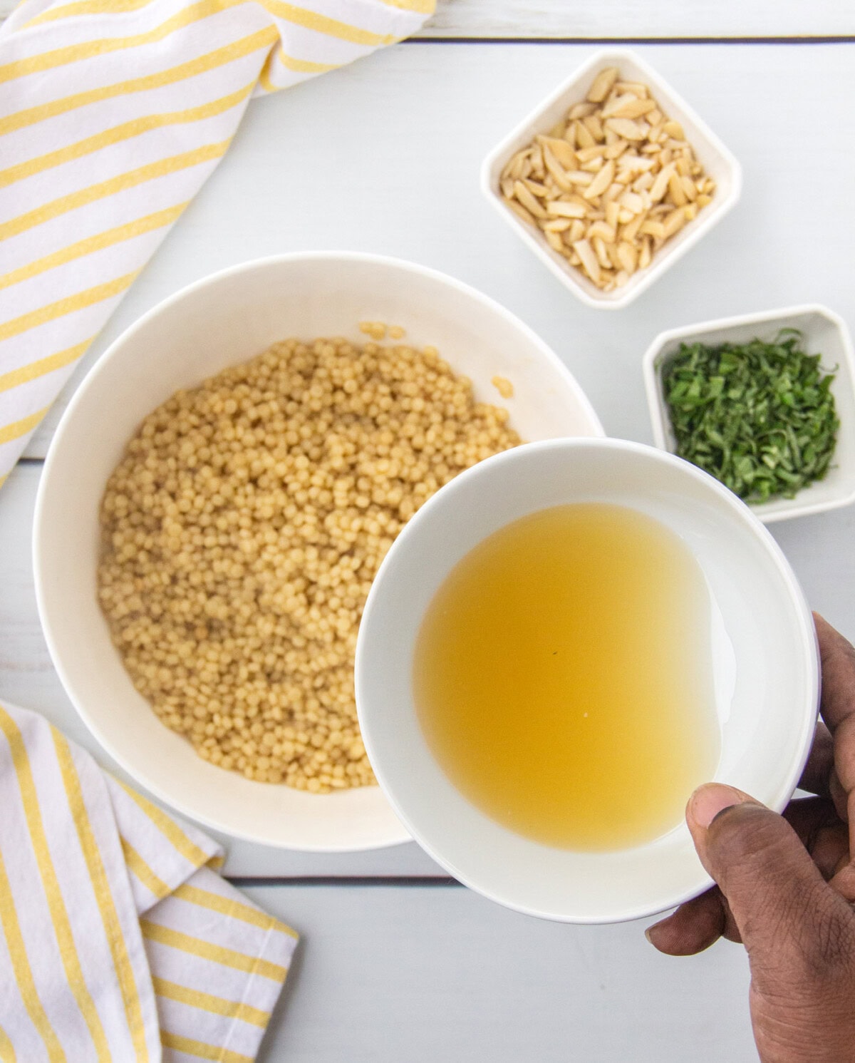 pouring lemon juice mixture, basil, and almonds to couscous