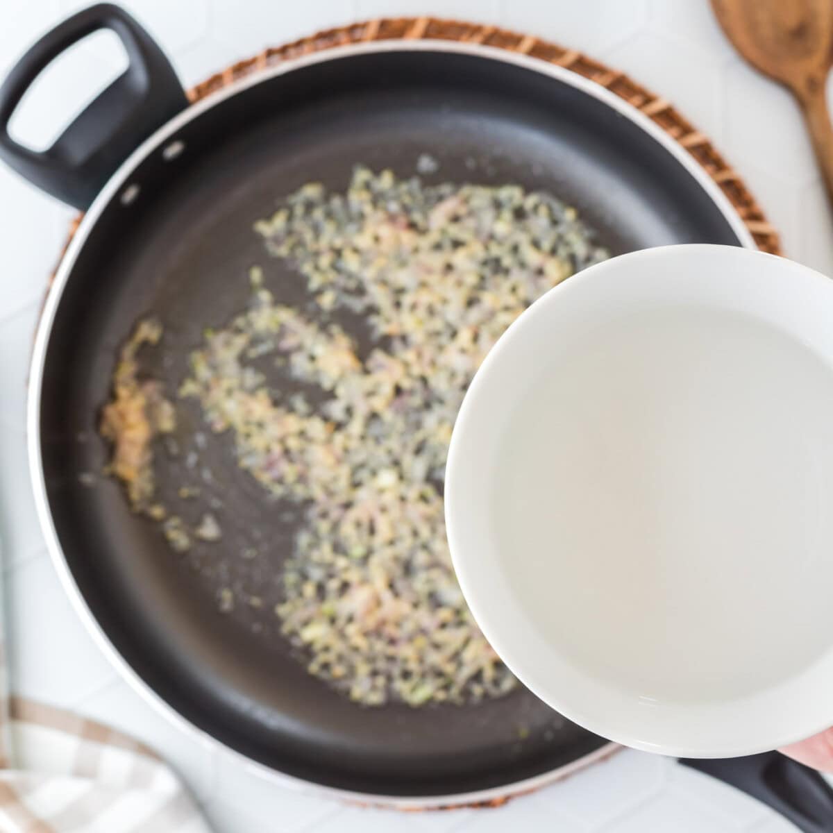 pouring water into pan with shallots and garlic