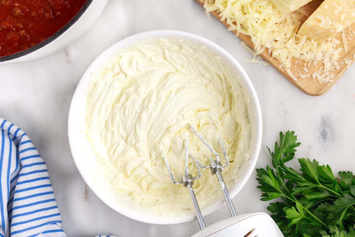 hand mixer mixing ricotta, cream cheese, and egg