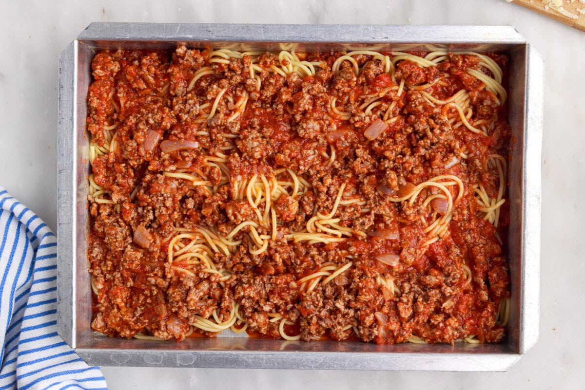 meat sauce on top of spaghetti in a baking dish