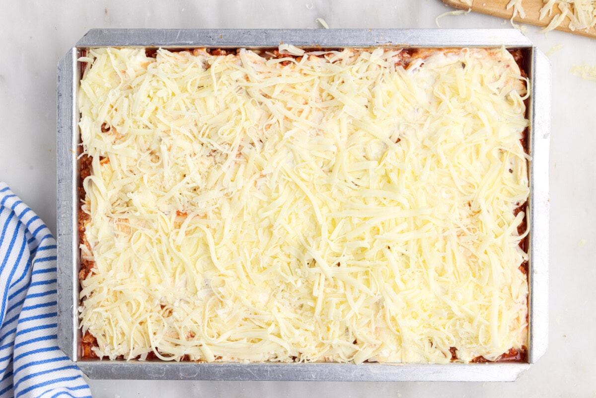 parmesan cheese on top of mozzarella, meat sauce, ricotta, and noodles