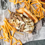 Philly Cheese Steak on parchment with fries