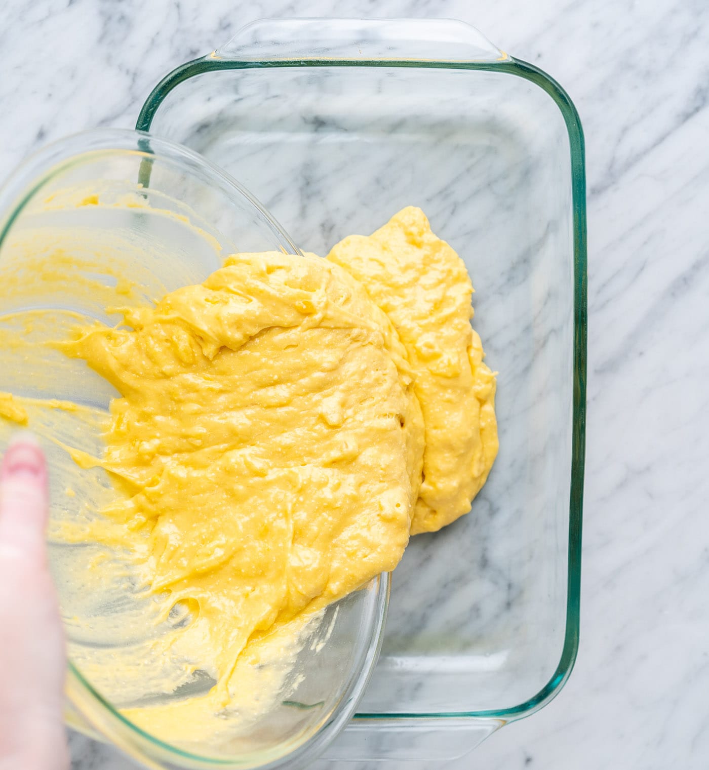 pouring pineapple cake batter into a baking dish