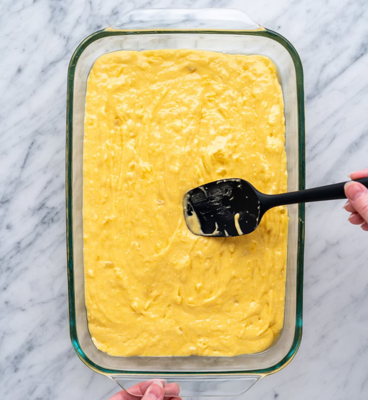 spreading pineapple cake batter into a baking dish