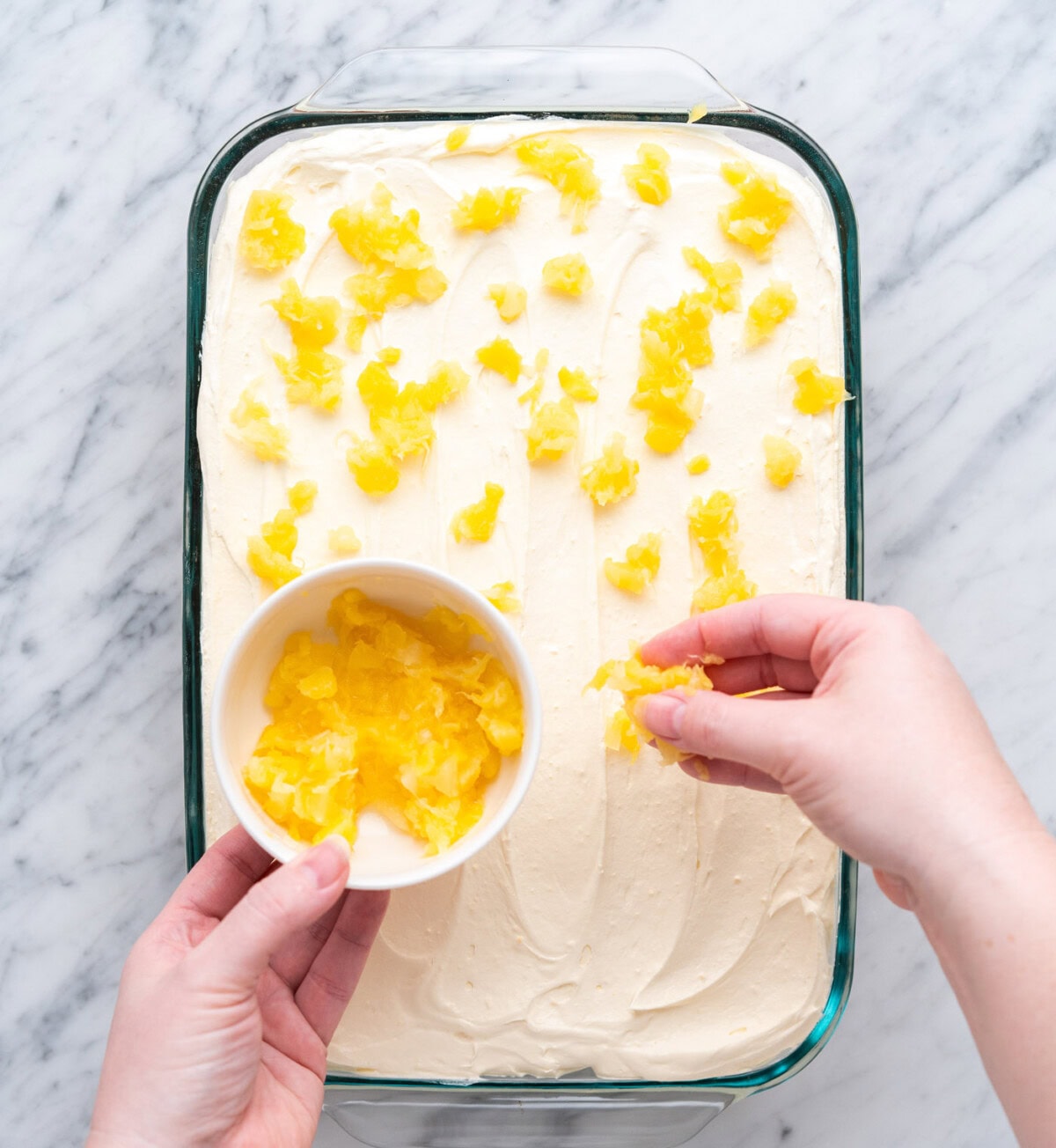 sprinkling pineapple on top of a cake