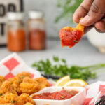 dipping a Popcorn Shrimp in cocktail sauce