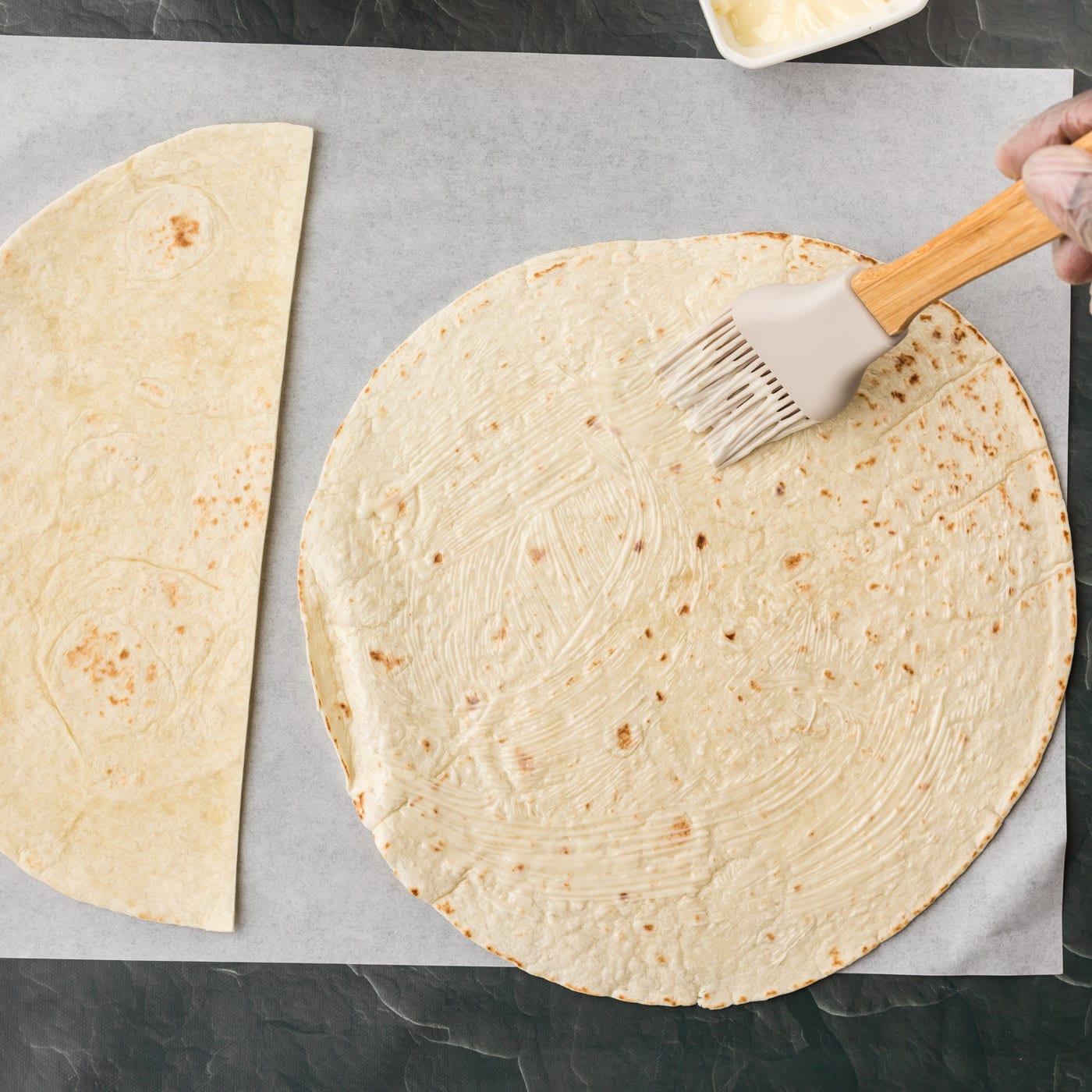brushing on softened butter to tortilla