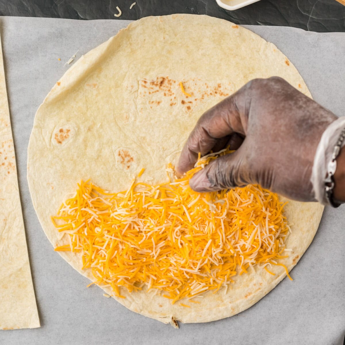 sprinkling cheese on flour tortilla