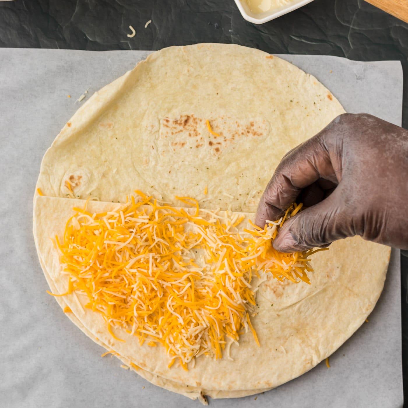 sprinkling cheese over folded quesadilla