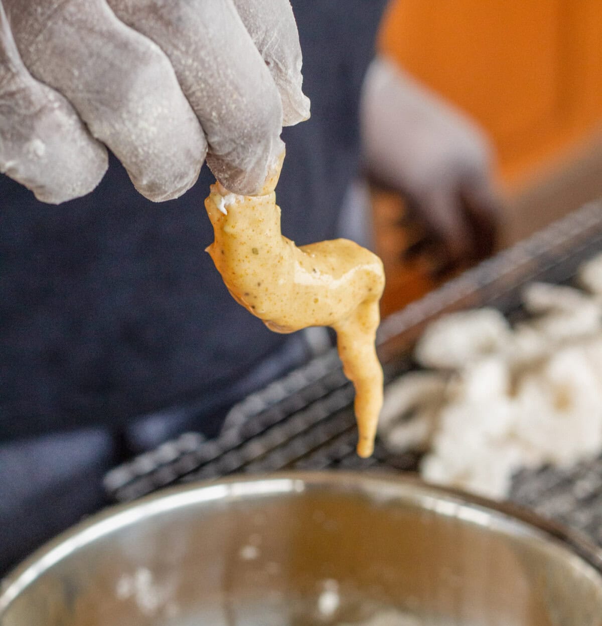 dipping flour dredged shrimp into seasoned egg mixture