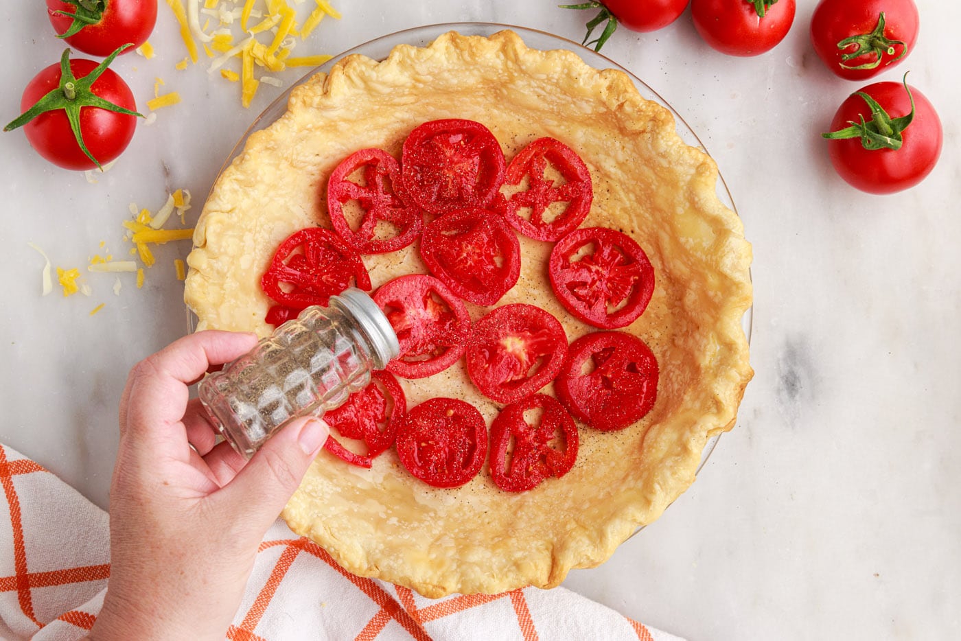 sprinkling black pepper on top of tomato pie