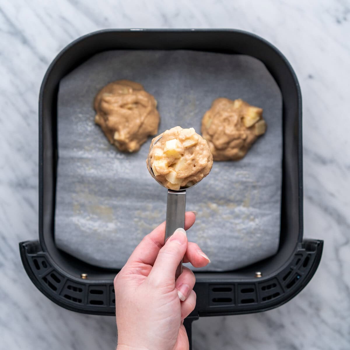 scoop of apple fritter batter over air fryer basket