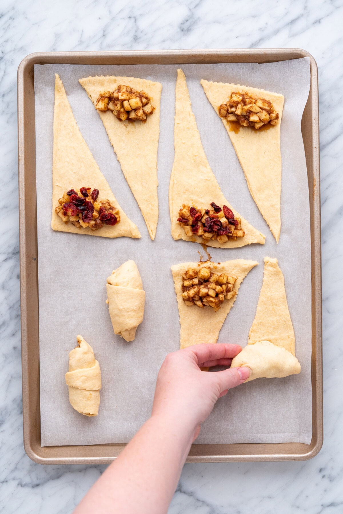 rolling up apple pie bites on baking sheet