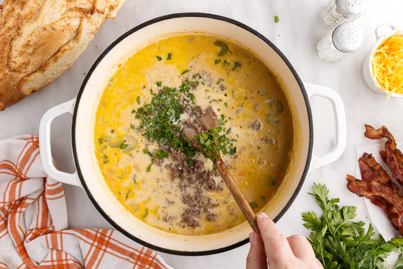 stirring cheeseburger soup in a pot
