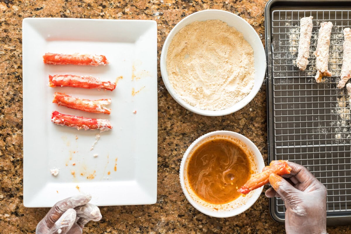 dipping crab leg into seasoned egg mixture