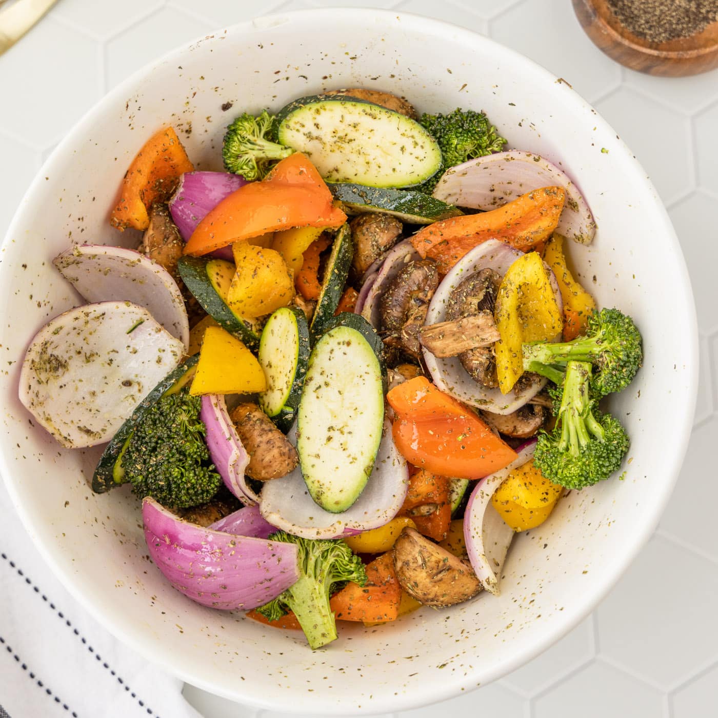 grilled vegetables tossed with olive oil and seasoning in a bowl
