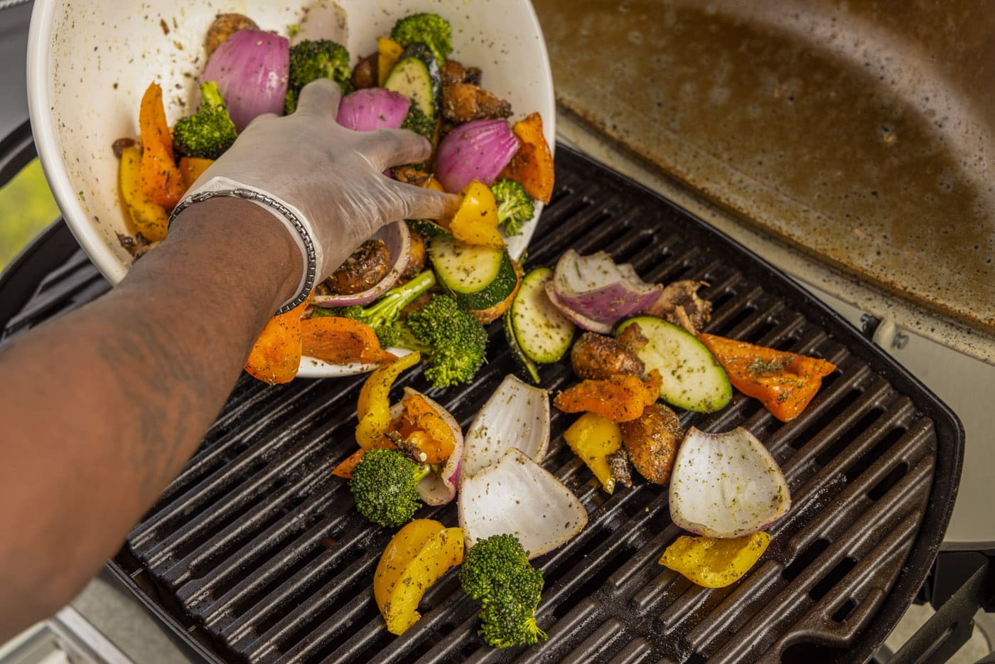hand placing vegetables onto grill grate