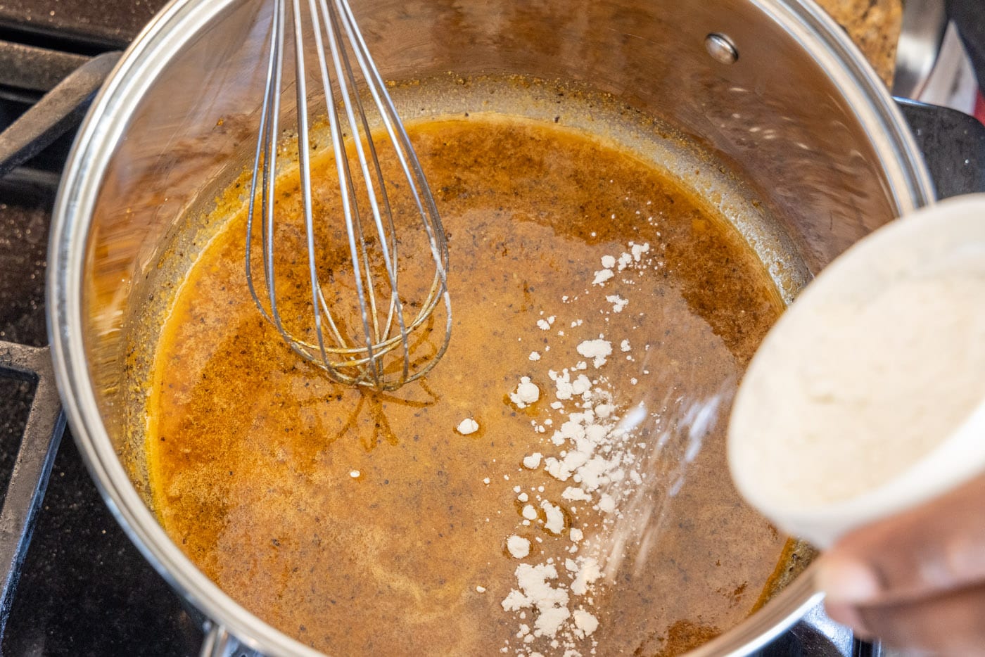 adding flour to roux with a whisk