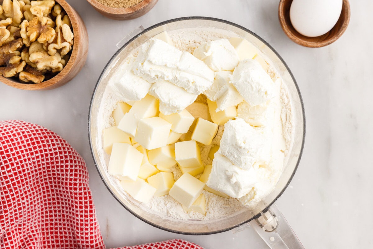 cream cheese and butter over flour in a food processor