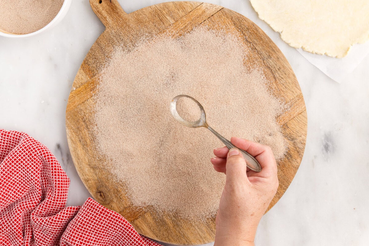 sprinkling cinnamon sugar over cutting board