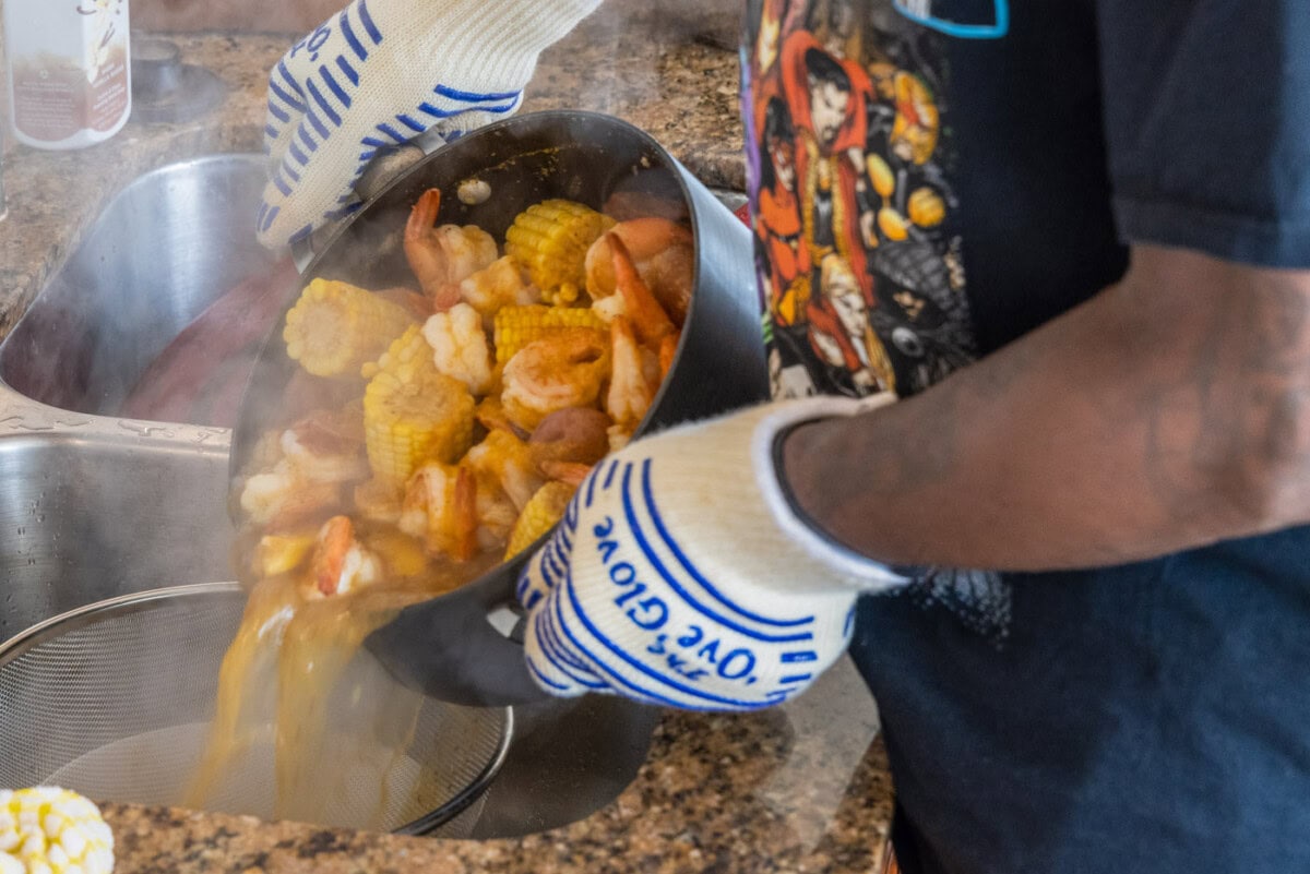 pouring shrimp boil over a colander