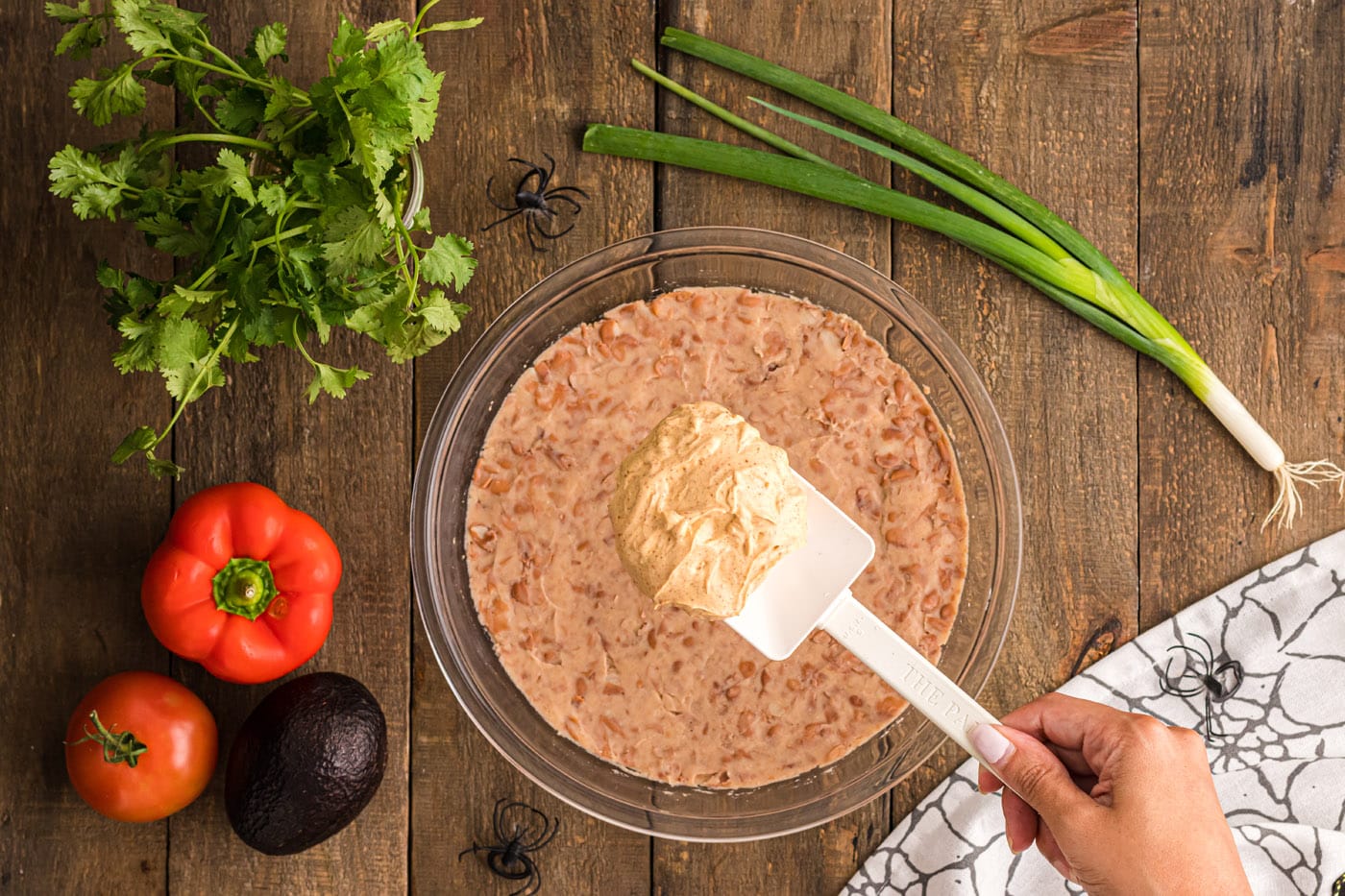 spreading cream cheese taco dip layer over refried beans