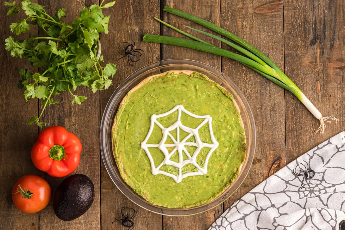 spiderweb sour cream on top of taco dip