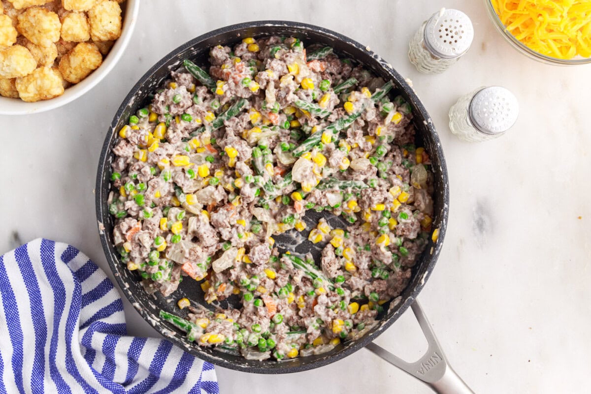 stirred tatertot casserole ingredients in a skillet