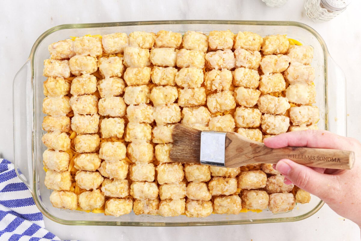 brushing melted butter over tatertots