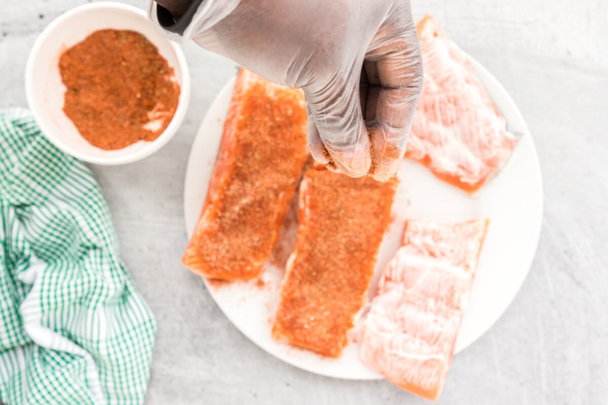 adding blackened seasoning to salmon filets