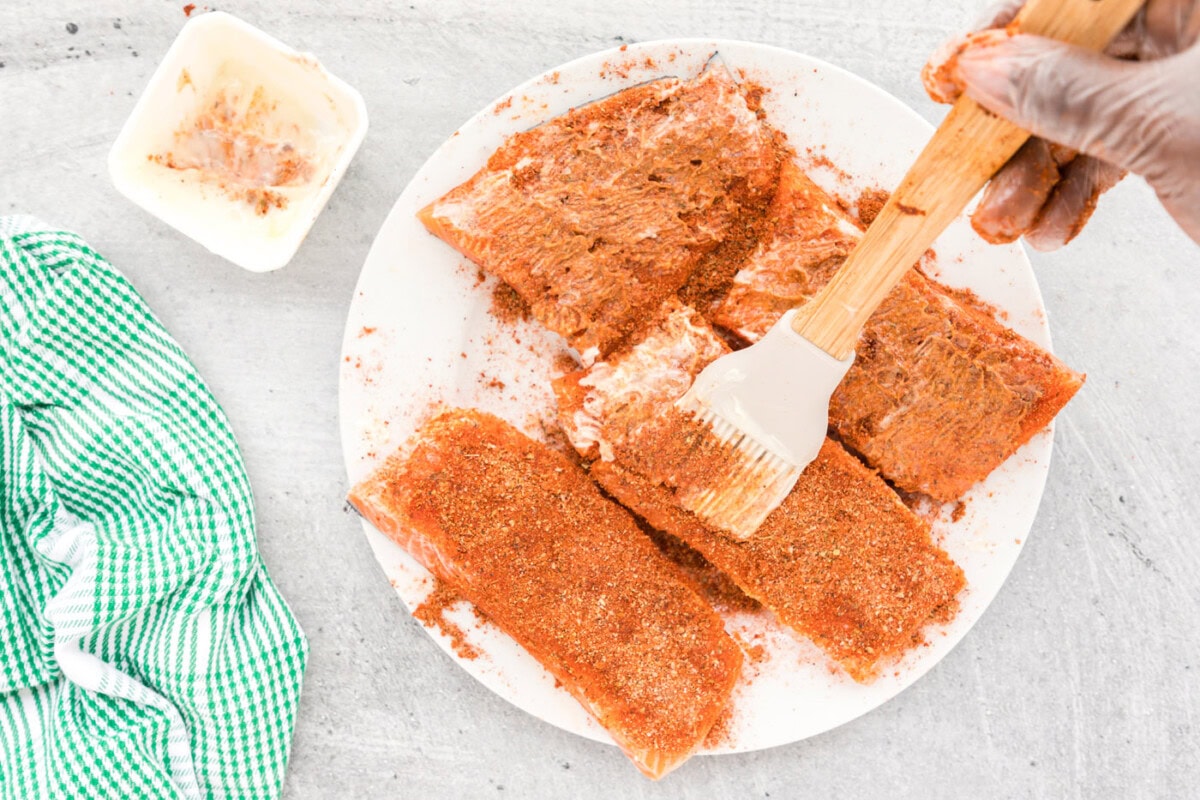 brushing butter over blackened seasoning on salmon